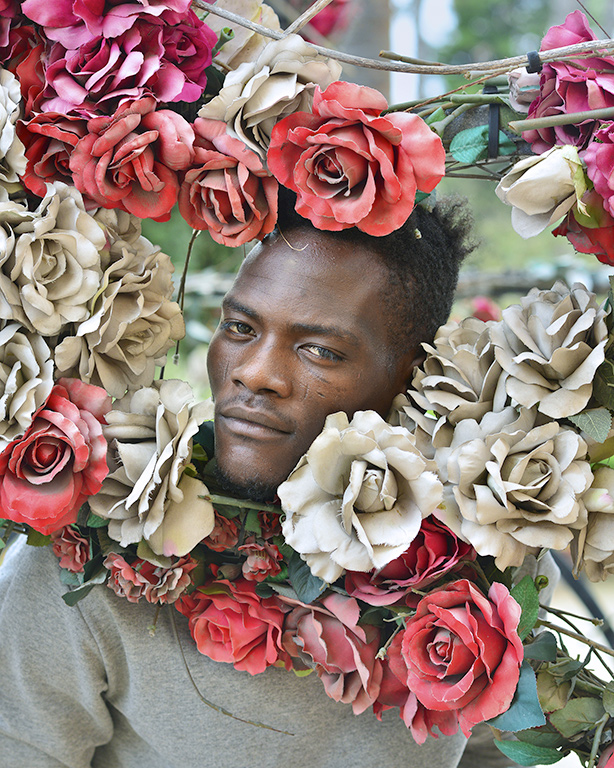 A portrait of a migrant surrounded by roses, on show for FOTOGRAFIA EUROPEA